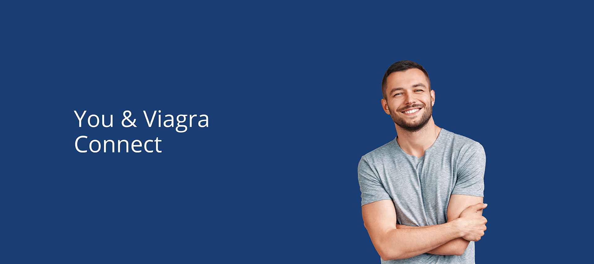 Man in his thirties, standing and smiling, looking relaxed and happy wearing a grey T shirt